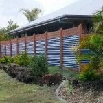 a blue and white striped fence in front of a house with palm trees on the side