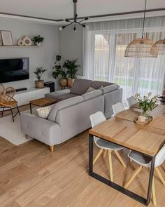 a living room filled with furniture and a flat screen tv mounted to the wall next to a wooden table