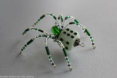 a green and white spider with black dots on it's legs sitting on a table