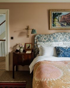 a bed sitting in a bedroom next to a wooden table with flowers on top of it