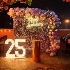 a birthday decoration with balloons and lights on the ground in front of a sign that reads 25