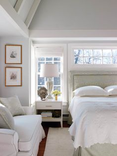 a white bed sitting in a bedroom next to two chairs