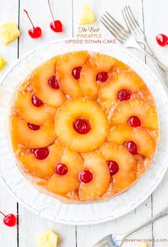 pineapple upside down cake with cherries in the middle on a white platter