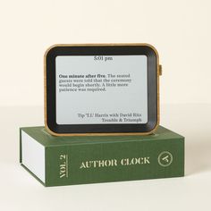 an electronic device sitting on top of a green book cover with the text author clock