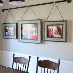 three framed pictures hang on the wall above a dining room table with four chairs and a bench