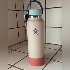 a white and blue water bottle sitting on top of a tile floor next to a tiled wall