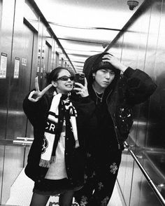 two people taking a selfie in an elevator while wearing winter clothes and scarfs