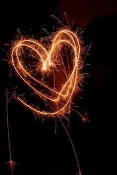 a heart made out of sparklers in the dark