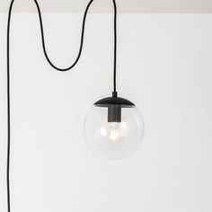 a light that is hanging from a wall with a cord attached to it and a glass ball on the end