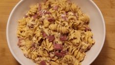 a white bowl filled with pasta and ham