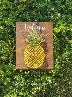 a wooden sign that says welcome with a potted plant