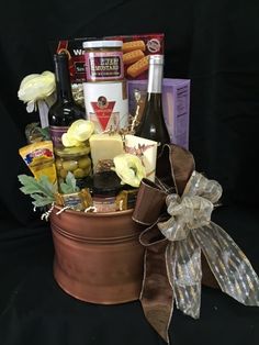 a gift basket with wine, cheese and other food items in it on a black background