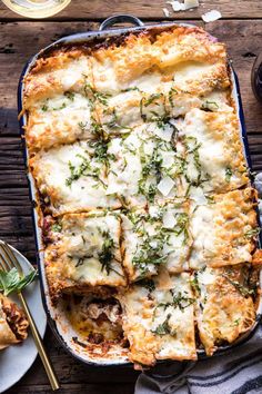 a casserole dish with cheese and herbs on top, next to two plates