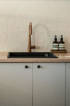 a kitchen sink sitting under a faucet next to a counter top with soap dispensers