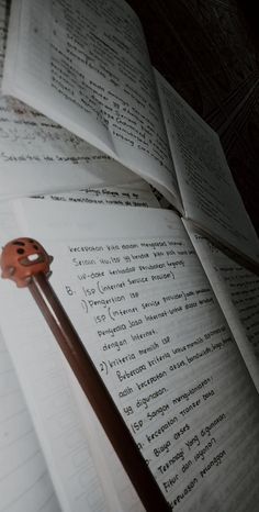 an open book with a pencil sticking out of it's middle next to a piece of paper