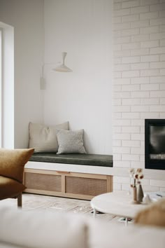 a living room with white brick walls and a window seat next to a fire place