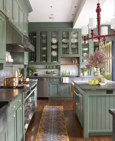 an image of a kitchen with green cabinets and wood floors in the middle of it