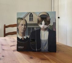 a cat sitting on top of a wooden table next to a painting of a woman