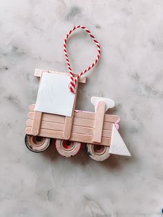 an ornament shaped like a toy truck on a marble surface with red and white striped twine