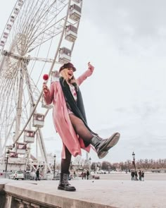 a woman standing on the edge of a pier next to a ferris wheel