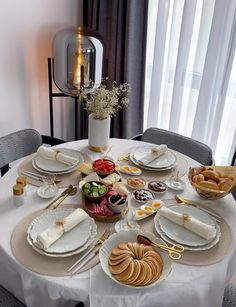 a white table topped with lots of plates and bowls filled with different types of food