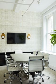 an empty conference room with white chairs and a flat screen tv mounted on the wall