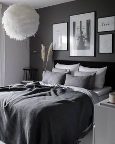 a bedroom with gray walls and pictures on the wall above the bed, along with a feathery lamp