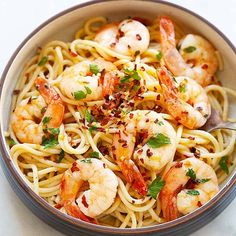 a bowl filled with pasta and shrimp on top of a white countertop next to a fork