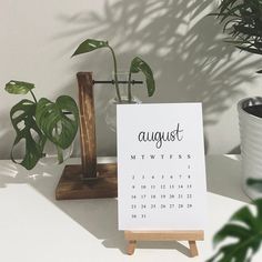 a calendar sitting on top of a wooden stand next to a potted plant