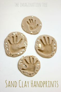 three clay handprinted magnets sitting on top of a white table next to each other