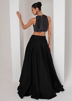 Introducing the stunning Black High Low Skirt with Nalki Blouse, crafted from luxurious taffeta silk. The black nalki blouse boasts a chic, sleeveless halter neck design, adorned with intricate halo nalki chain embellishments that add a touch of shimmer and sophistication. Paired perfectly with a flowing, solid black high-low skirt, creating an ensemble that effortlessly merges modern elegance with traditional charm. Ideal for Cocktails, Sangeet nights, or evening parties, this outfit is designed to make you stand out with its sleek silhouette and striking contrast. Composition : Skirt, Blouse - Taffeta Silk Care: Dry Clean Only and Vacuum Storage This product can be customized for sleeves, blouse length and neckline Delivery : 4-6 weeks as the product is hand crafted. Check Size Guide or Elegant Sleeveless Embellished Lehenga, Silk Festive Evening Skirt, Fitted Taffeta Party Skirt, Fitted Taffeta Skirt For Parties, Festive Evening Halter Neck Dress, Black Silk Skirt For Gala, Elegant Satin Lehenga For Party, Elegant Satin Lehenga For Evening, Elegant Evening Satin Lehenga