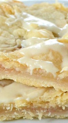 two pieces of dessert sitting on top of a white plate with icing and toppings