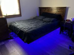 a bed sitting in a bedroom next to a window with blue lights on the floor