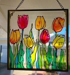 a stained glass window with flowers in the center hanging from a chain on a house