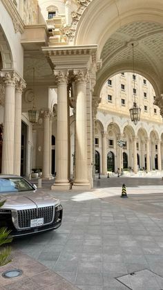 a car parked in front of a building with columns and arches on the side of it