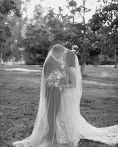 a bride and groom standing together in the grass at their outdoor wedding ceremony, black and white photograph