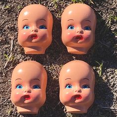 four baby doll heads laying on the ground with their mouths open and eyes wide open