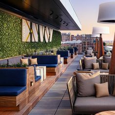 an outdoor seating area on the roof of a building with plants growing on the wall