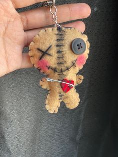 a hand holding a keychain with a small stuffed animal on it's side