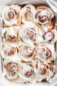 a pan filled with cinnamon rolls covered in icing