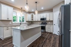 an empty kitchen with white cabinets and granite counter tops