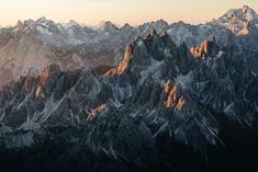 the mountains are covered in snow and light from the sun shining on them, as seen from an airplane