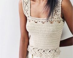 a woman wearing a white crochet top with her hands on her hips and looking at the camera