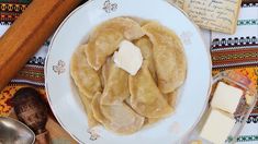 a white plate topped with ravioli and cheese next to butter on top of a table