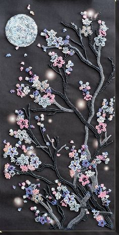 an embroidered art piece with flowers and a full moon in the background, on black fabric