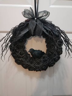 a black wreath with a bird on it hanging from the front door, next to a white door