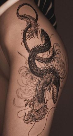 the back of a woman's thigh with a dragon tattoo on her leg and an arm