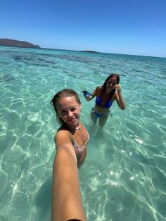 two women in the water taking pictures with their cell phones