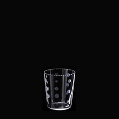 a black and white photo of a glass with polka dots on the bottom, against a dark background