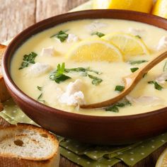 a bowl of soup with bread and lemons